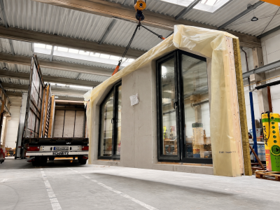 Transport prefabrykowanej ściany domu z dużymi przeszkleniami na hali produkcyjnej